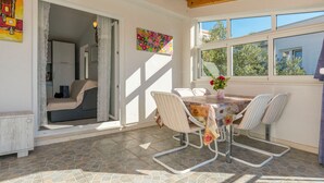 A sunlit room with a dining table, chairs, and a view of the outside. - House Osti (Rogoznica)