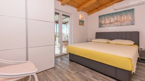 A bedroom with a bed, a chair, a sliding glass door, and a painting on the wall. - House Osti (Rogoznica)