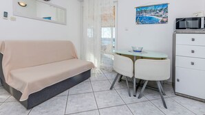 A room with a sofa, a small table with chairs, a microwave, and a poster on the wall. - House Osti (Rogoznica)