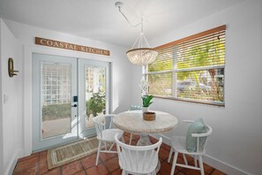 Un coin cuisine situé près de la côte, avec une table ronde, des chaises blanches et un luminaire suspendu.