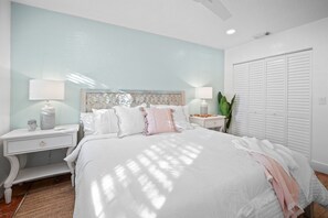 Une chambre à coucher comprenant un lit, deux tables de chevet, une commode, un grand miroir et un placard.