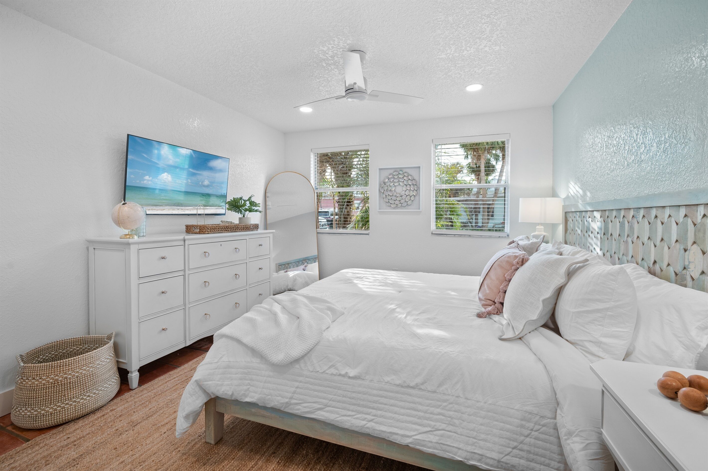 A bedroom with a bed, dresser, and a ceiling fan.