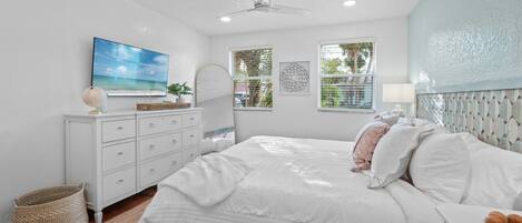 A bedroom with a bed, dresser, and a ceiling fan.