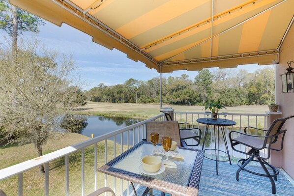 A balcony with a table set for two, overlooking a body of water and trees.