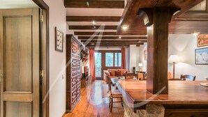 A spacious room with a wooden floor, a large wooden dining table, and a stone accent wall.
