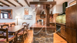 A kitchen with wooden cabinets, a stone island, and a dining area with wooden chairs and a table.