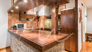 A kitchen with a stone island, wooden cabinetry, a microwave, and a sink.