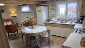 Une cuisine chaleureuse avec une table de salle à manger ronde, des chaises, un vase de fleurs, un réfrigérateur, un évier et une cuisinière.