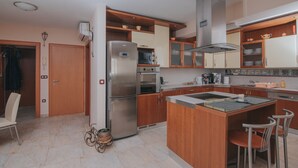Eine moderne Küche mit Holzausstattung, Edelstahlgeräten und einer zentralen Kochinsel mit Sitzgelegenheiten.