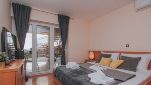 Ein Hotelzimmer mit Bett, Schreibtisch, Fernseher und einer Glastür zum Balkon.