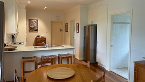 A modern kitchen with a central island, stainless steel refrigerator, and wooden dining table. - ☘️"KILMEEDY" Take time to smell the roses🌹 in Bowral-Walk to town-Pet friendly. (Bowral)