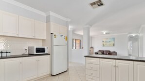 A modern kitchen with white cabinets, a microwave, and a refrigerator. - Mandurah Estuary Breeze (Wannanup)