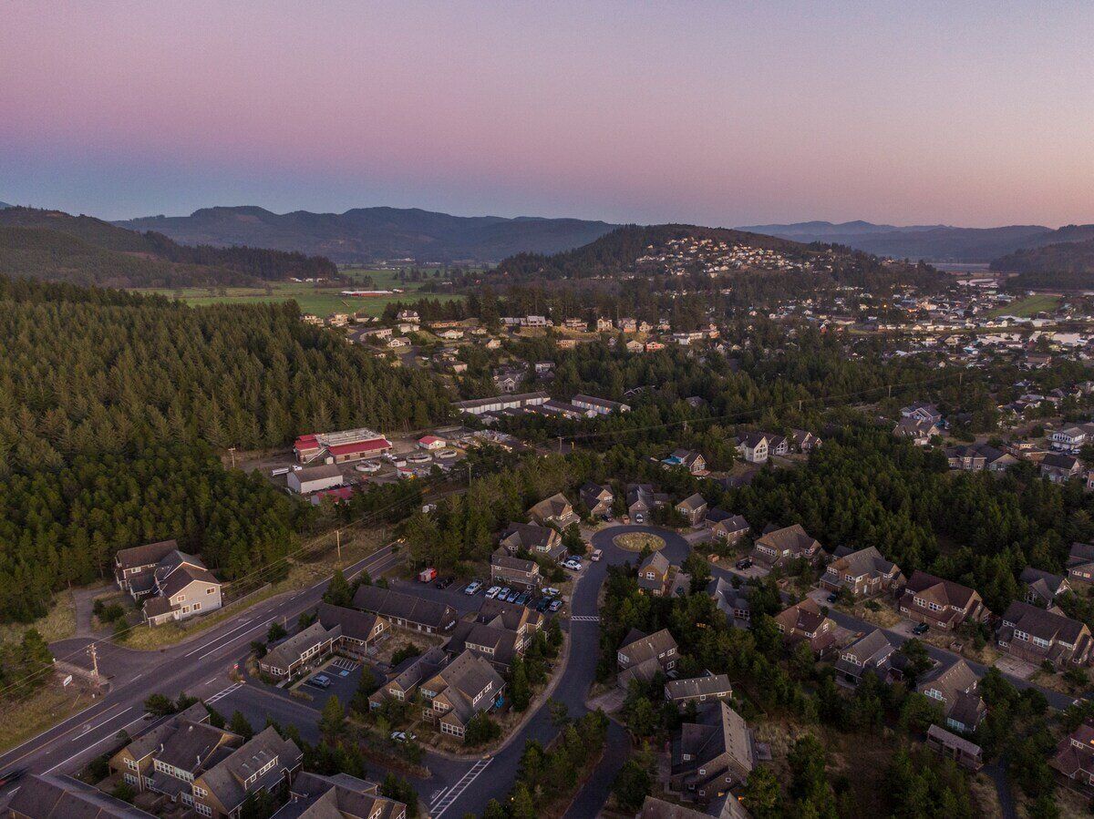 Vue aérienne d’un quartier résidentiel avec des maisons, des rues et un petit bâtiment commercial.