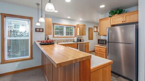 A modern kitchen with wooden cabinets, a stainless steel refrigerator, and a wooden island. - Seaside Paradise - lovely townhome, beach paths, dog OK (Pacific City)