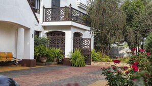 A courtyard with a white building, a wooden bench, potted plants, and a pathway.