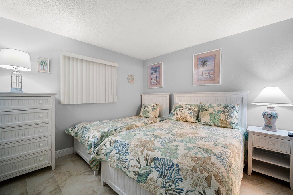 A bedroom with two beds, a dresser, a nightstand, and wall art.