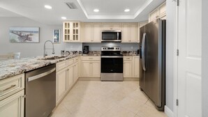 Una cocina moderna con armarios de colores claros, electrodomésticos de acero inoxidable y encimera de granito.