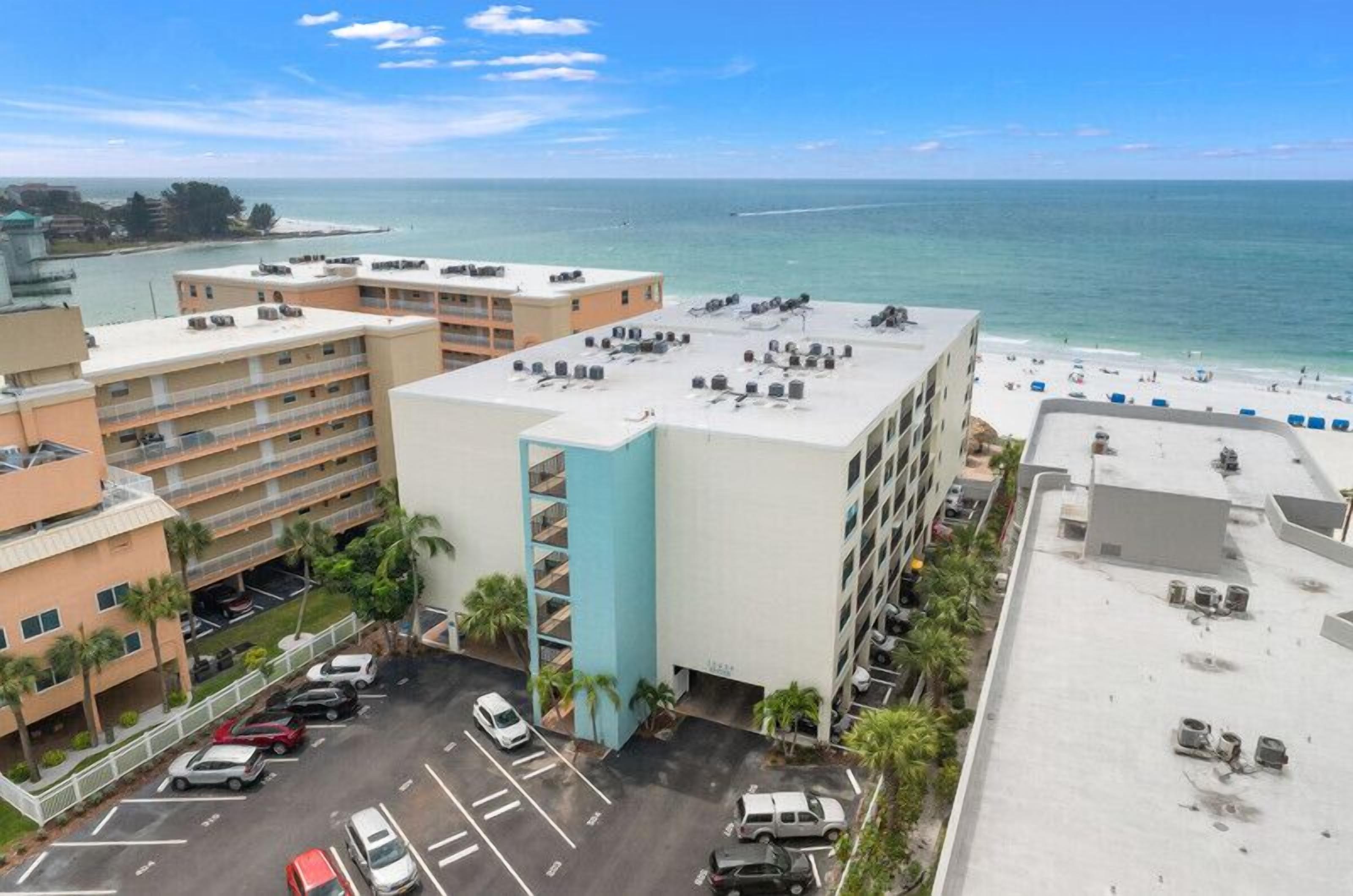 Un hotel de varios pisos, con estacionamiento y vista a la playa y al océano.
