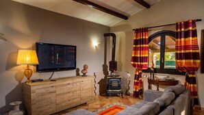 A living room with a sofa, a TV, a wooden cabinet, a fireplace, and curtains.