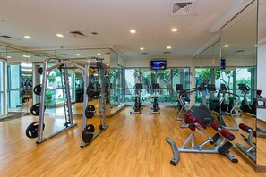 A gym with various exercise equipment, large windows, and a television on the wall. - HiGuests - Boulevard Central Tower (Dubai)