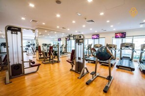 A gym with various exercise machines, treadmills, and a mirrored wall. - HiGuests - Boulevard Central Tower (Dubai)