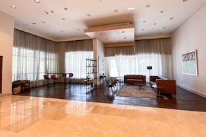 A spacious living room with a large window, a sofa, a coffee table, and a bookshelf. - HiGuests - Boulevard Central Tower (Dubai)