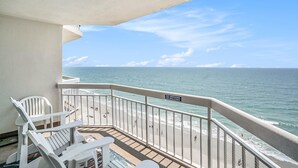 A balcony with white chairs and a 'No Smoking' sign, overlooking a beach with people and the ocean. - 1004 Waters Edge Resort 1 Bedroom Condo by RedAwning (Murrells Inlet)