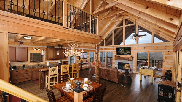 A spacious wooden cabin with a dining area, kitchen, and a loft bedroom with a balcony. - Moose-n Around: Cut Loose in the Smokies (Sevierville)