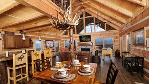 A spacious wooden dining area with a high ceiling, a mounted television, and a fireplace. - Moose-n Around: Cut Loose in the Smokies (Sevierville)
