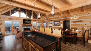 A spacious log cabin interior with a large kitchen area, wooden dining table, and a cozy seating area. - Moose-n Around: Cut Loose in the Smokies (Sevierville)