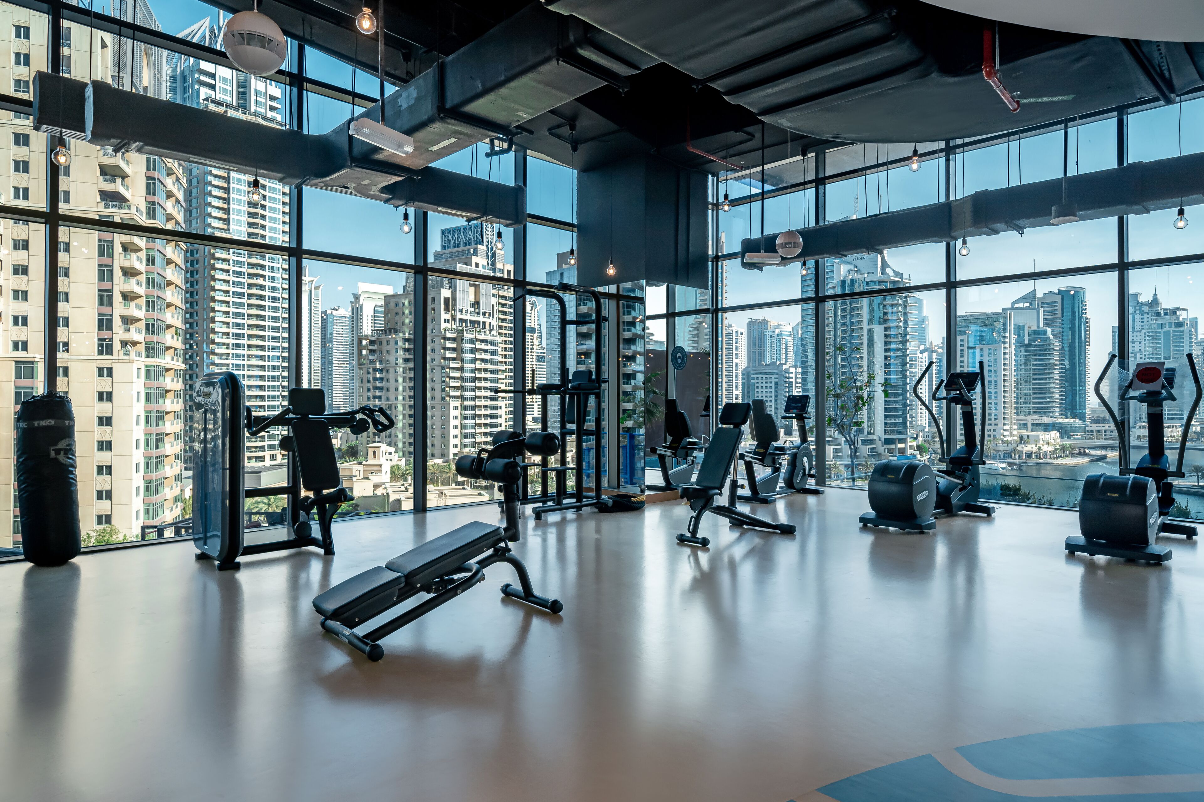 A gym with various exercise equipment, large windows, and a city view.