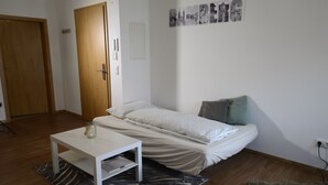 A small, clean room with a bed, a white table, and a rug.