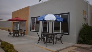 An outdoor seating area with tables and chairs, a red umbrella, and a blue and white umbrella with "BLUE BELL ICE CREAM" written on it.