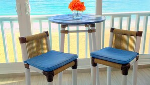 A balcony with two wicker chairs and a small table with a vase of flowers. - The Happy Place (San Juan)