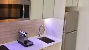 A modern kitchen with a microwave, sink, and refrigerator. - The Happy Place (San Juan)