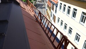 A balcony with a view of adjacent buildings and a clear sky.