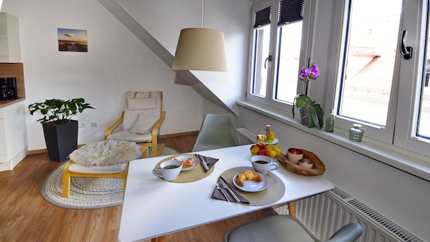 A dining area with a table set for breakfast, a chair, a lamp, and a window with a view.