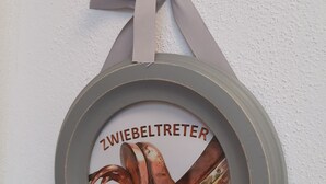 A circular wall decoration with a ribbon tied at the top.