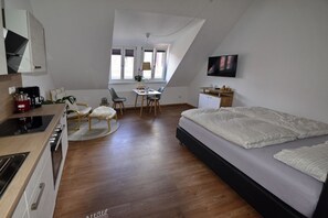 Une chambre moderne avec un grand lit, un bureau et un coin cuisine.
