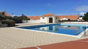 A swimming pool with a tiled deck, surrounded by buildings with red-tiled roofs. - Rental with heated swimming pool 800m from the sea  (Brem-sur-Mer)