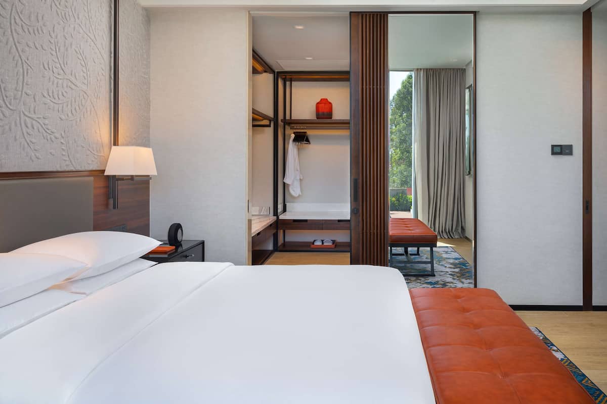 A hotel room with a large bed, a bedside table with a lamp, a wardrobe, and a television.