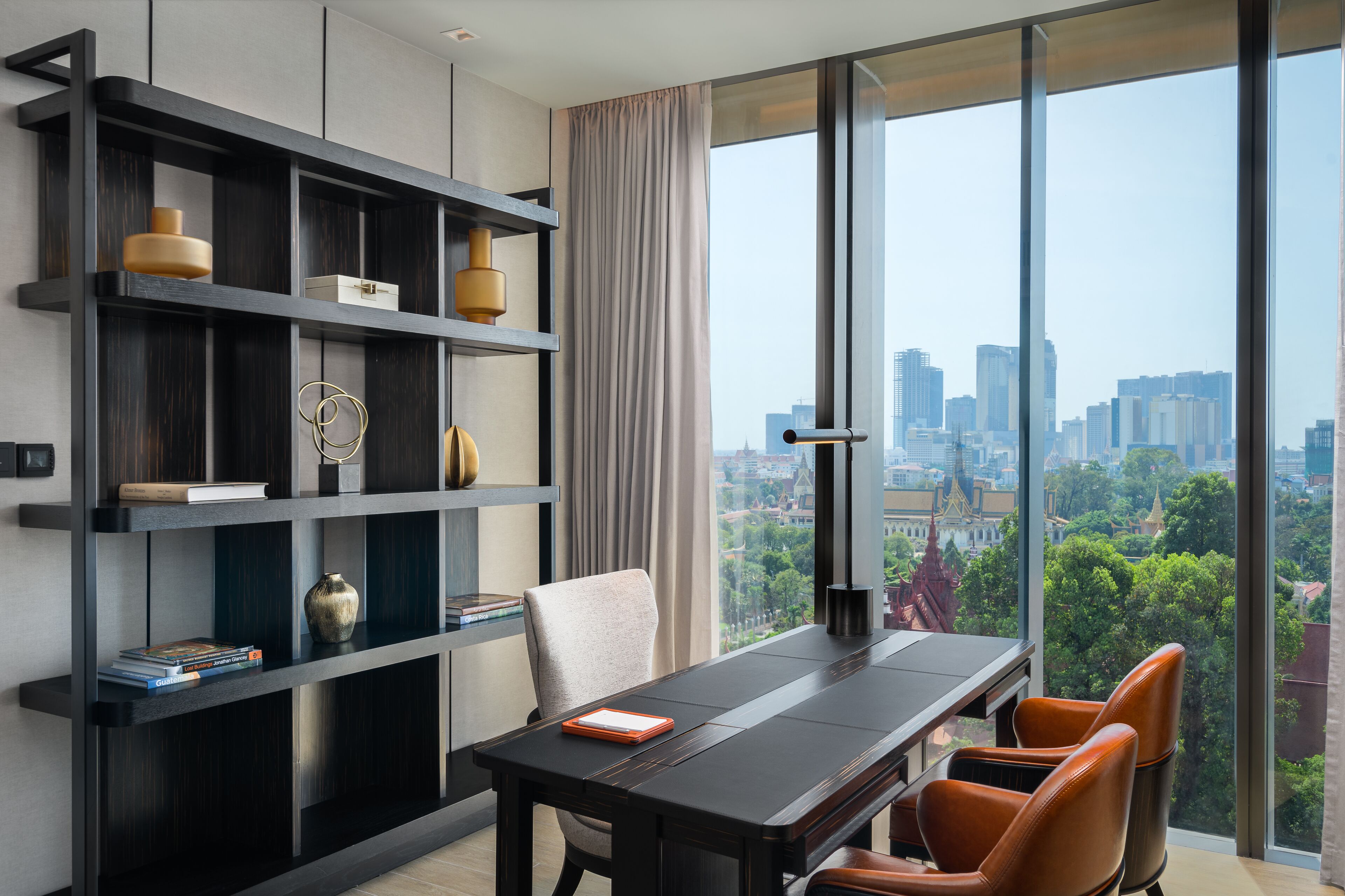 Ein modernes Zimmer mit großem Fenster, einem Esstisch und einem Bücherregal.