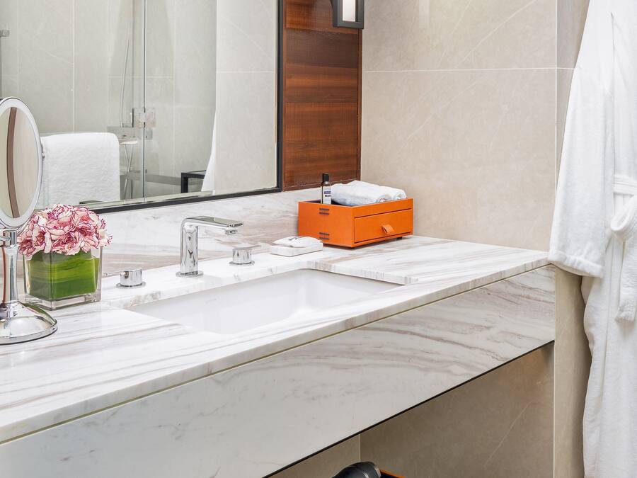 Uma casa de banho moderna com um espelho grande, duas bacias, um chuveiro e um porta-toalhas.