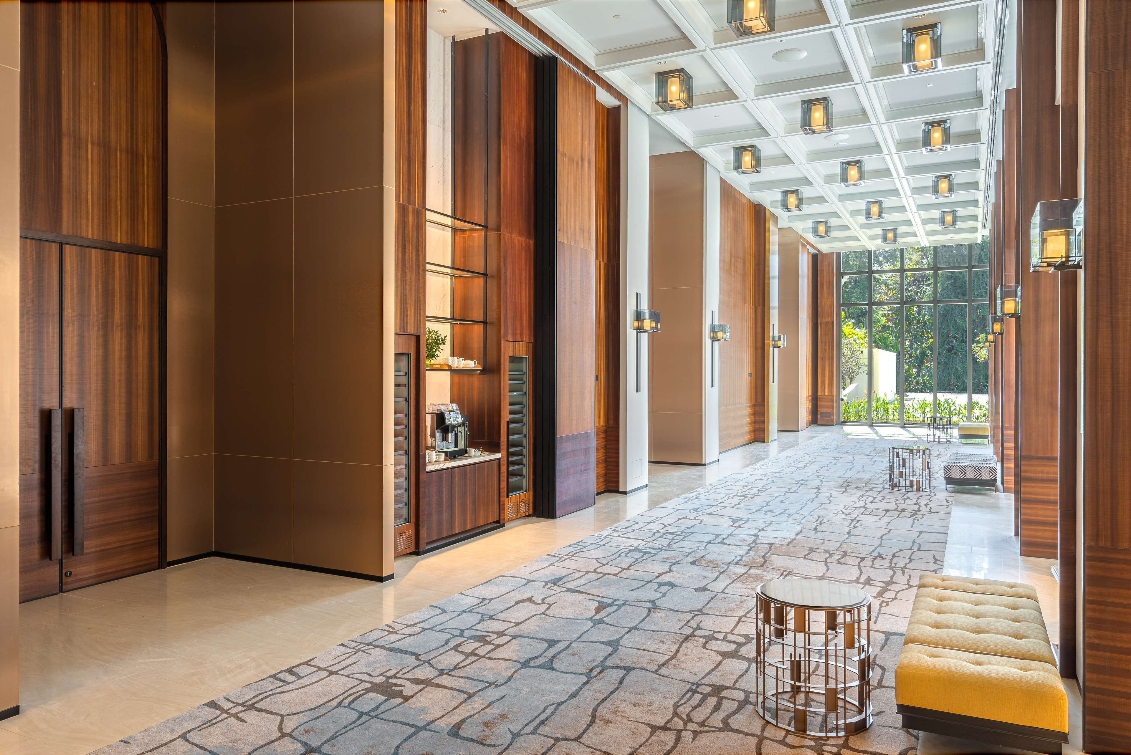 A spacious lobby with a stone-patterned floor, wooden paneling, and a seating area with a yellow bench.