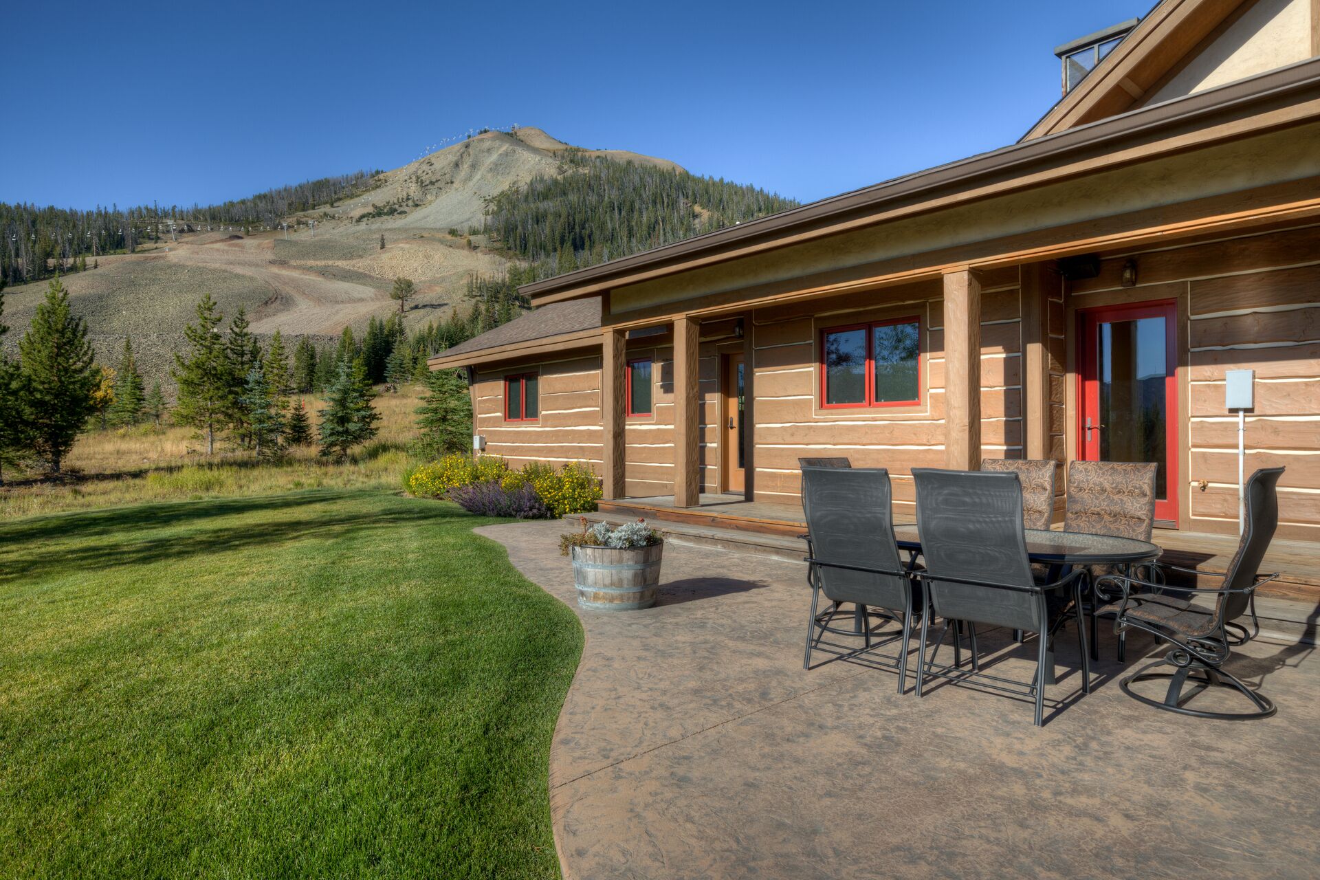 A log cabin with a patio, outdoor seating, and a view of a mountain.