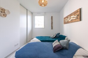 A bedroom with a bed, a window, a wall-mounted artwork, and a ceiling light fixture. - L'Elégance (Nice)