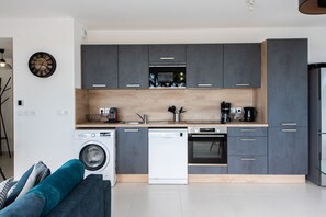 Une cuisine moderne avec des meubles de couleur grise, un lave-vaisselle, un four et une machine à café.