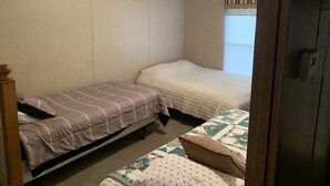 A bedroom with two single beds, a window with blinds, and a door.
