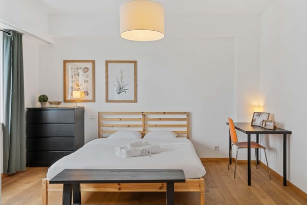 Rest in comfort in our beautifully appointed bedroom, featuring stylish decor and a cozy workspace.