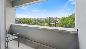 En balkong med utsikt över en stadsbild, inklusive byggnader och träd.